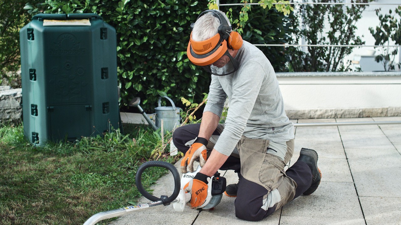 La débroussailleuse à essence STIHL&nbsp;FS&nbsp;38 est maintenue fermement au sol par une personne portant des vêtements de protection