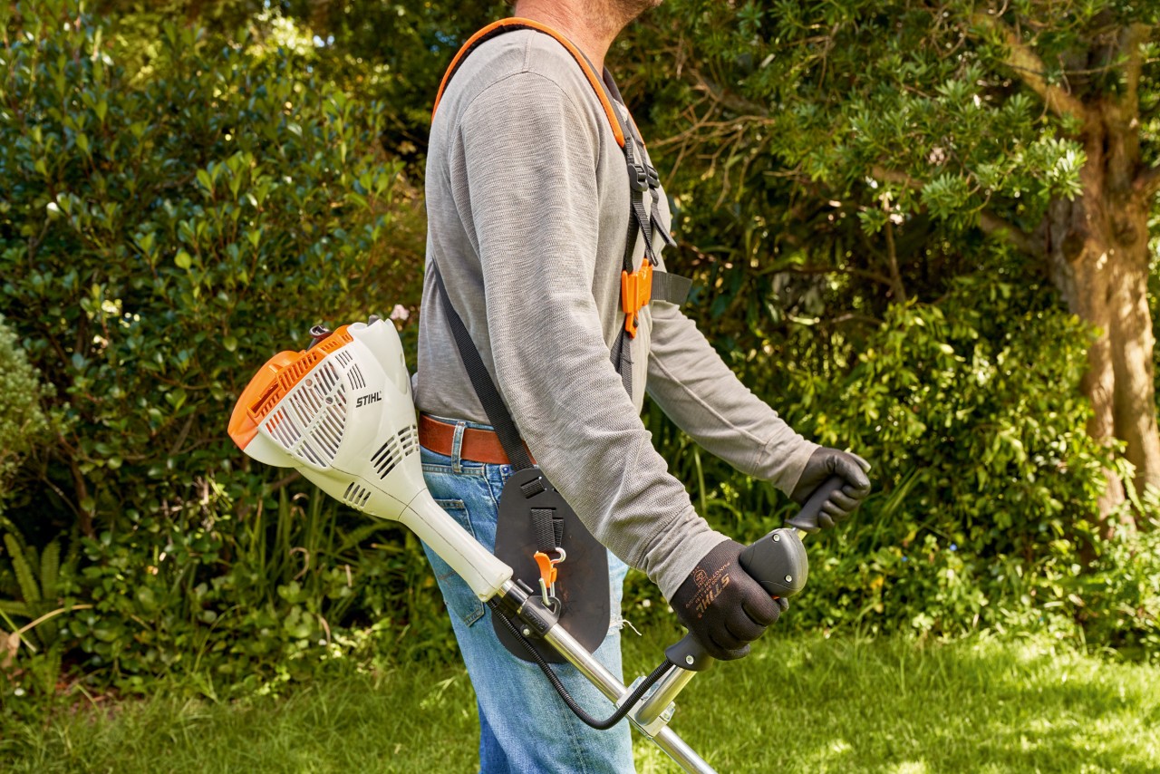 Un homme soulevant la débroussailleuse à essence STIHL&nbsp;FS&nbsp;56 du sol