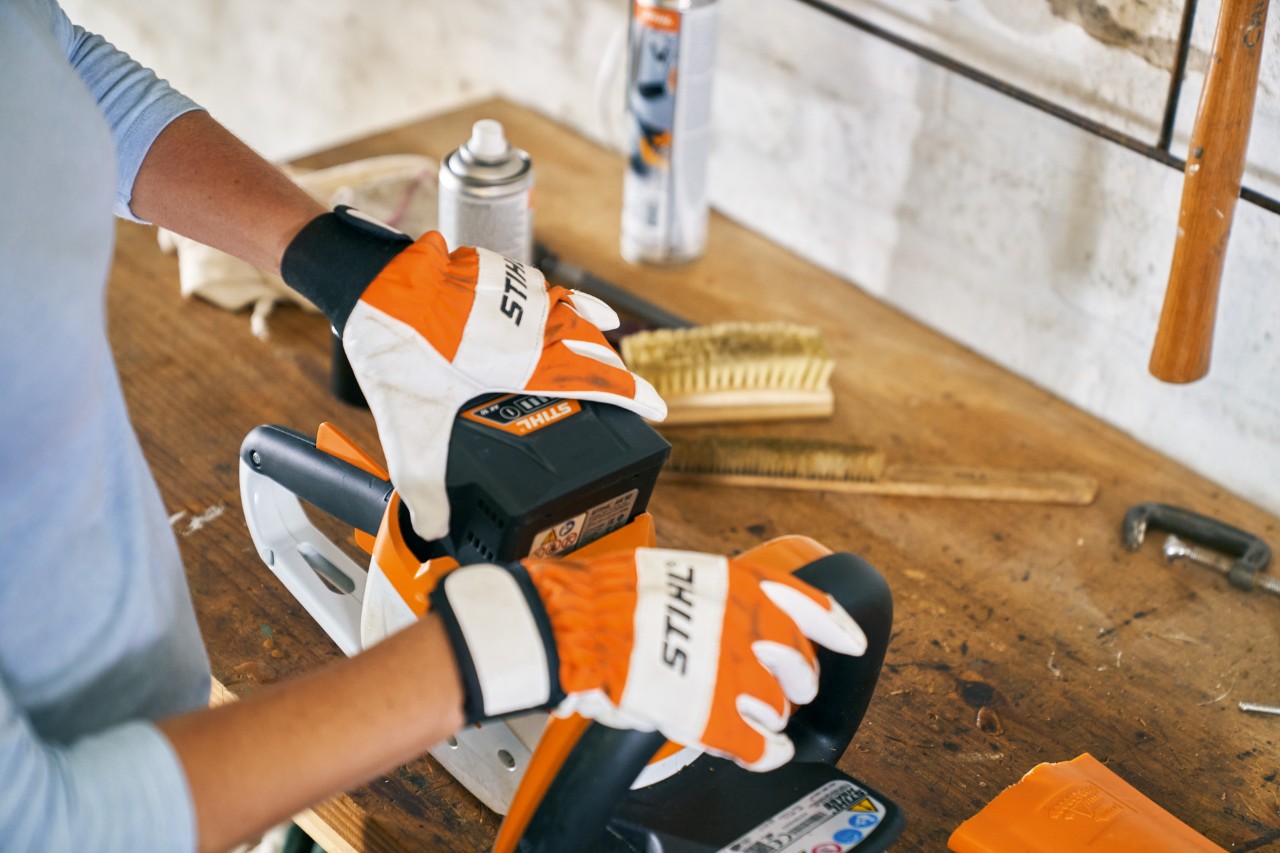 Personne portant des gants et travaillant sur le taille-haie à batterie STIHL HSA 56 