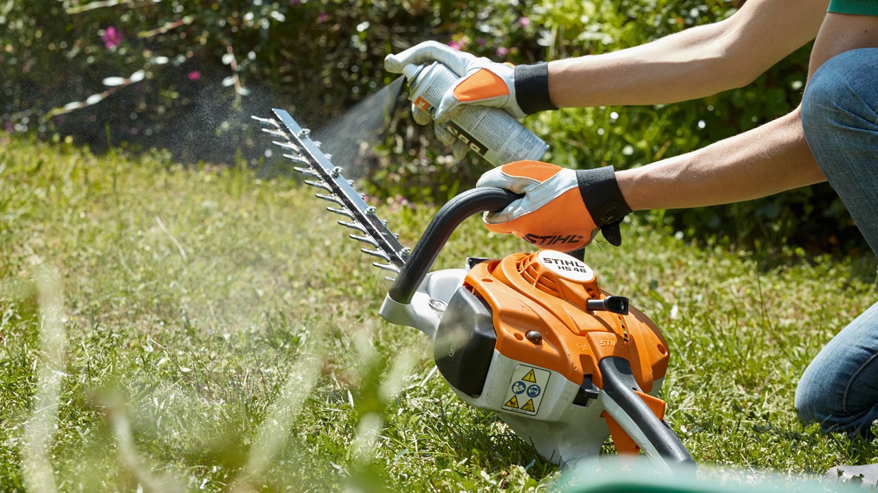 Le taille-haies thermique STIHL HS 82 T est aspergé sur une pelouse verte pour son nettoyage