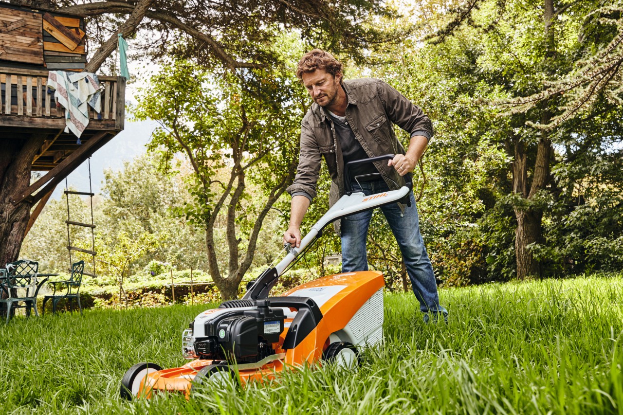 Un homme en train de tondre une pelouse avec une tondeuse thermique STIHL RM 448 TC