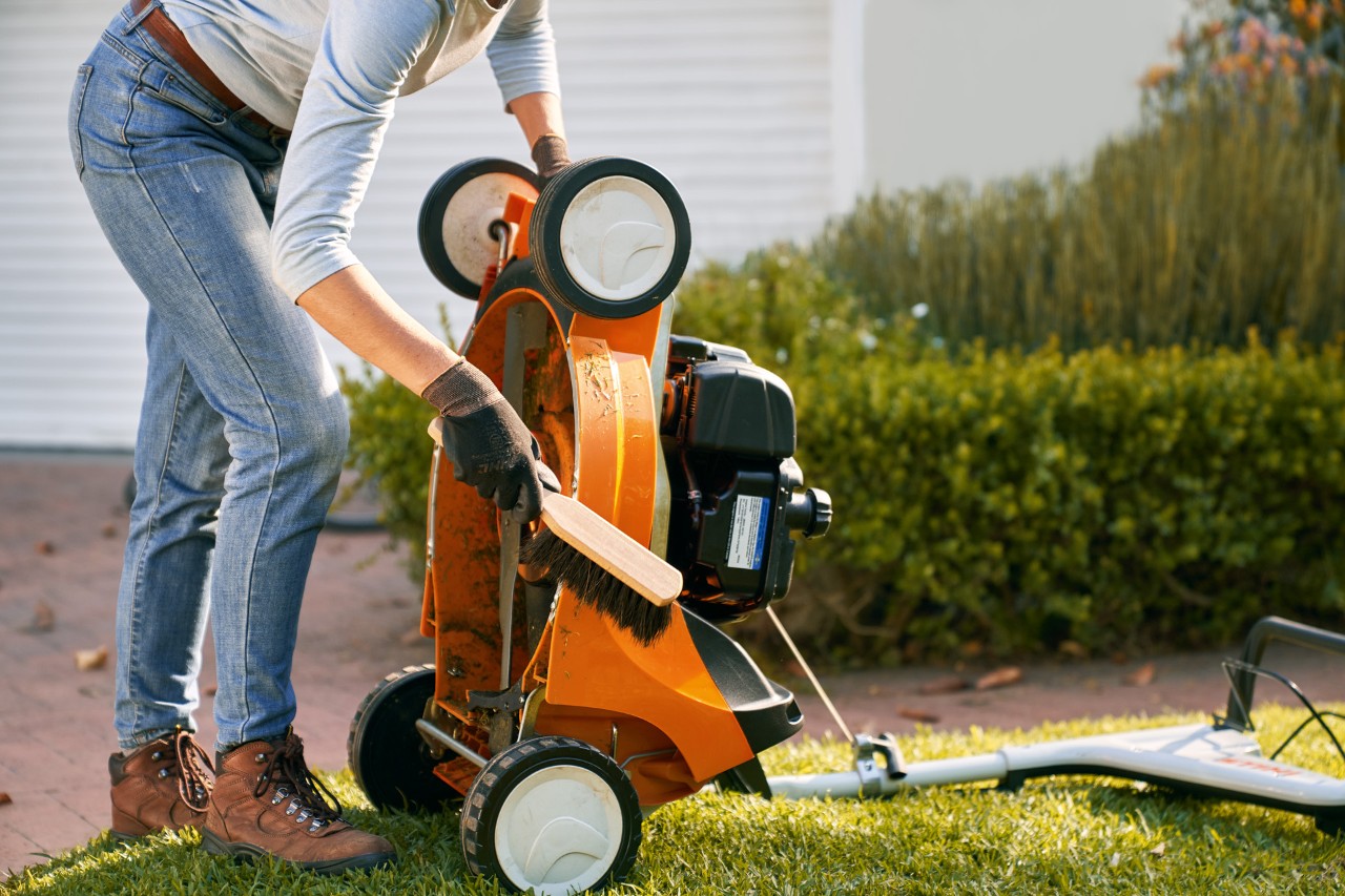 Nettoyage à la brosse d’une tondeuse thermique STIHL RM 448 T-C inclinée