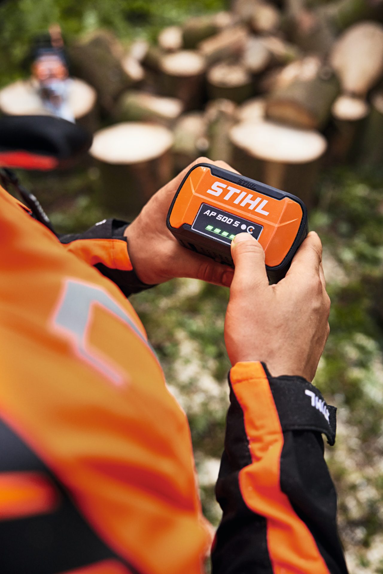 Gros plan sur une personne coupant un tronc d’arbre avec la tronçonneuse à batterie STIHL MSA 300