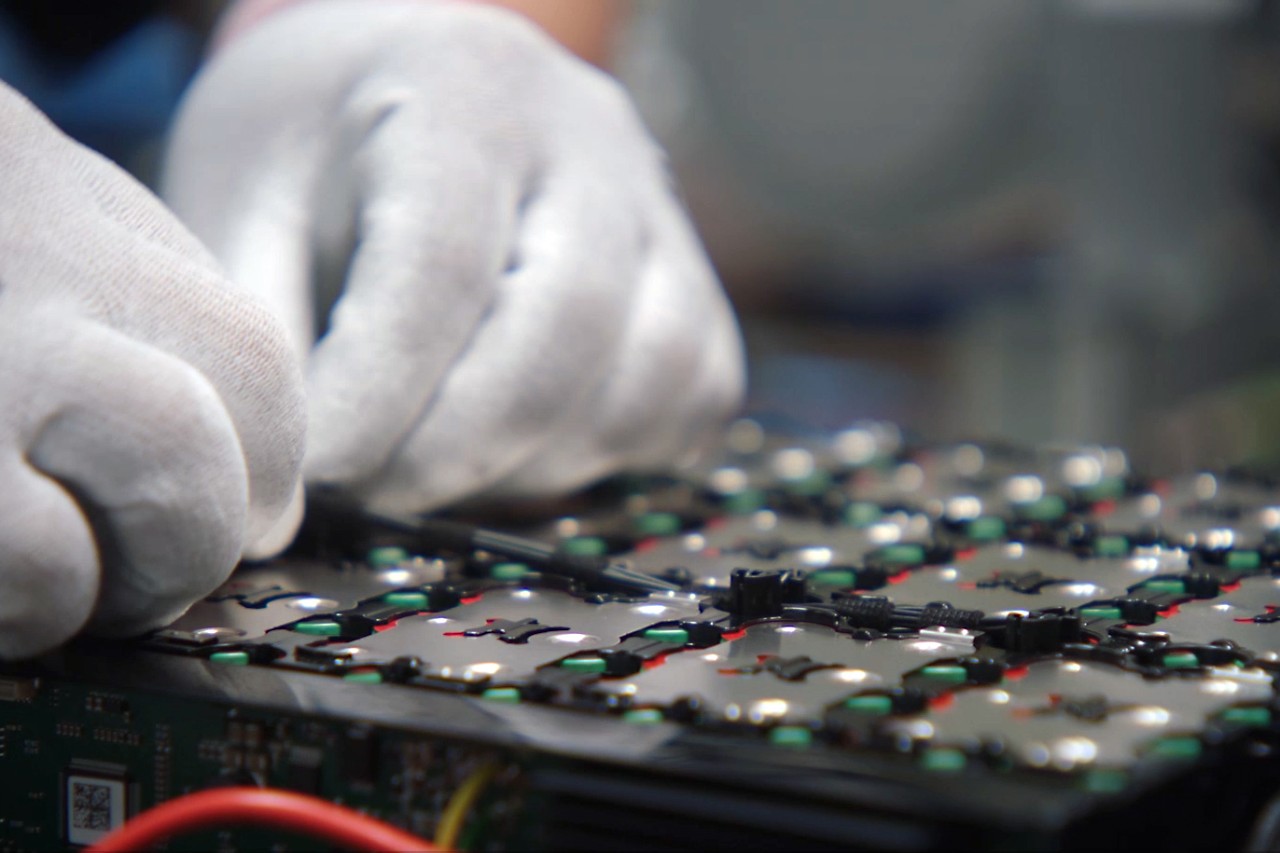 Gros plan sur une personne portant des gants de travail et installant des capteurs sur la batterie