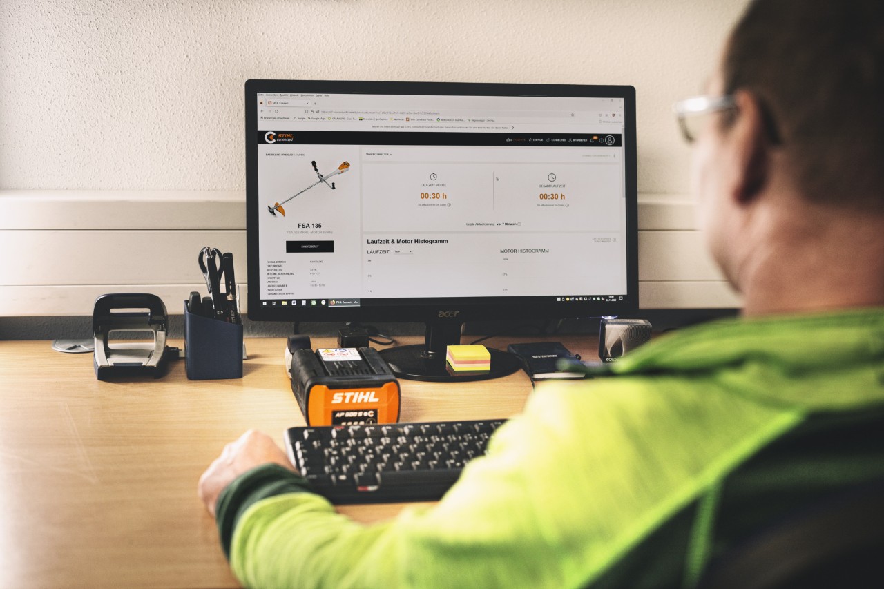 Homme assis à un bureau devant son ordinateur, l’écran affichant la page du portail STIHL connected