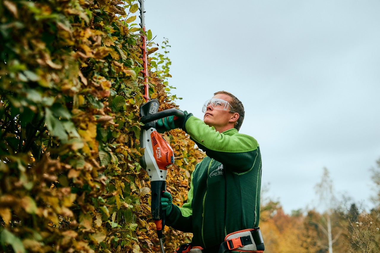 Un homme taille une haie avec un outil STIHL connecté
