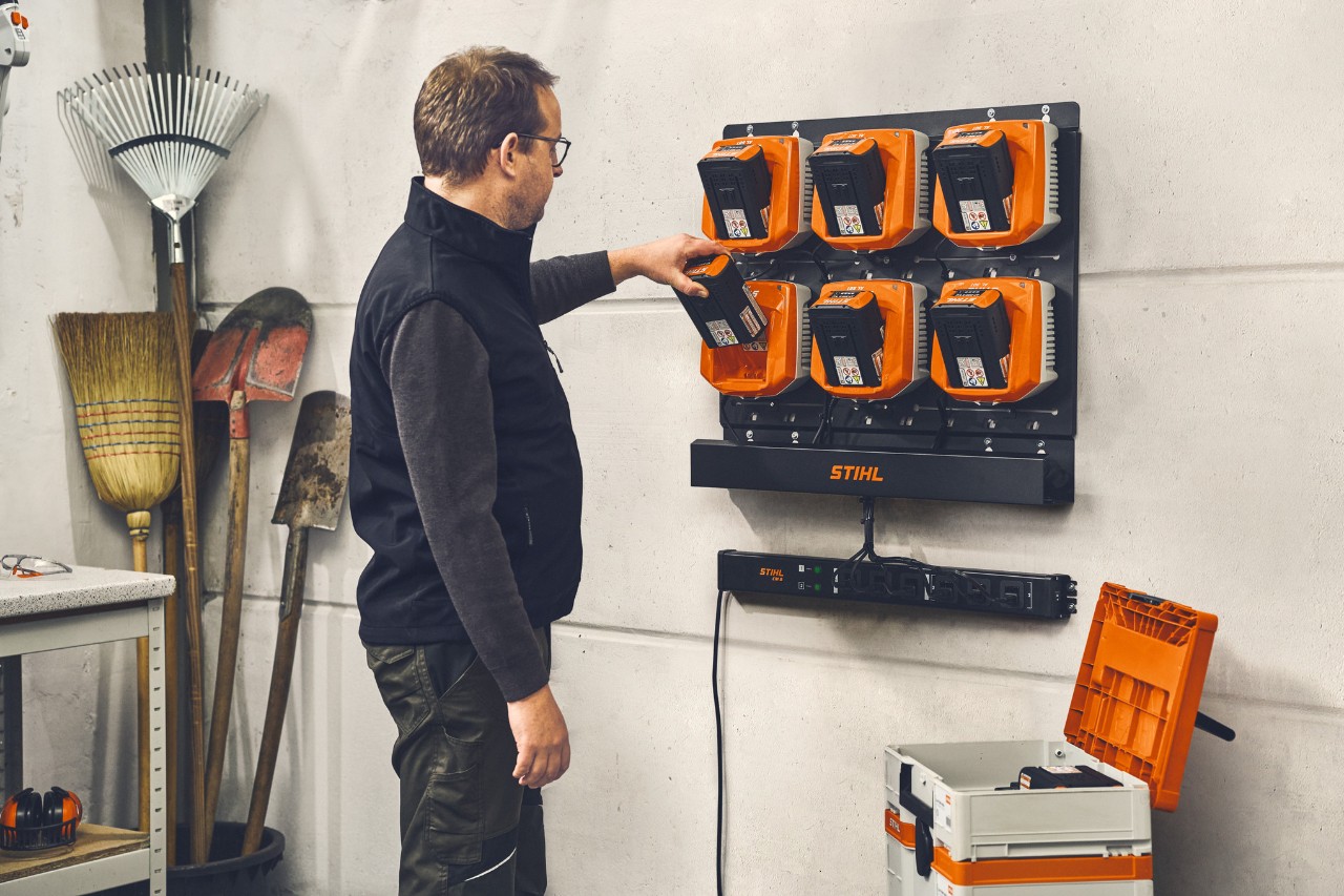 Système de gestion de charge STIHL CM 10 à montage mural, support mural STIHL CR 6 et chargeur STIHL AL 301 en cours d’utilisation.