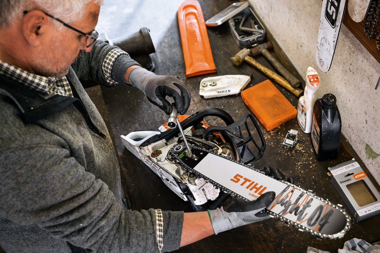 Revendeur spécialisé STIHL entretenant une tronçonneuse avec guide-chaîne STIHL Light 04 et chaîne Oilomatic