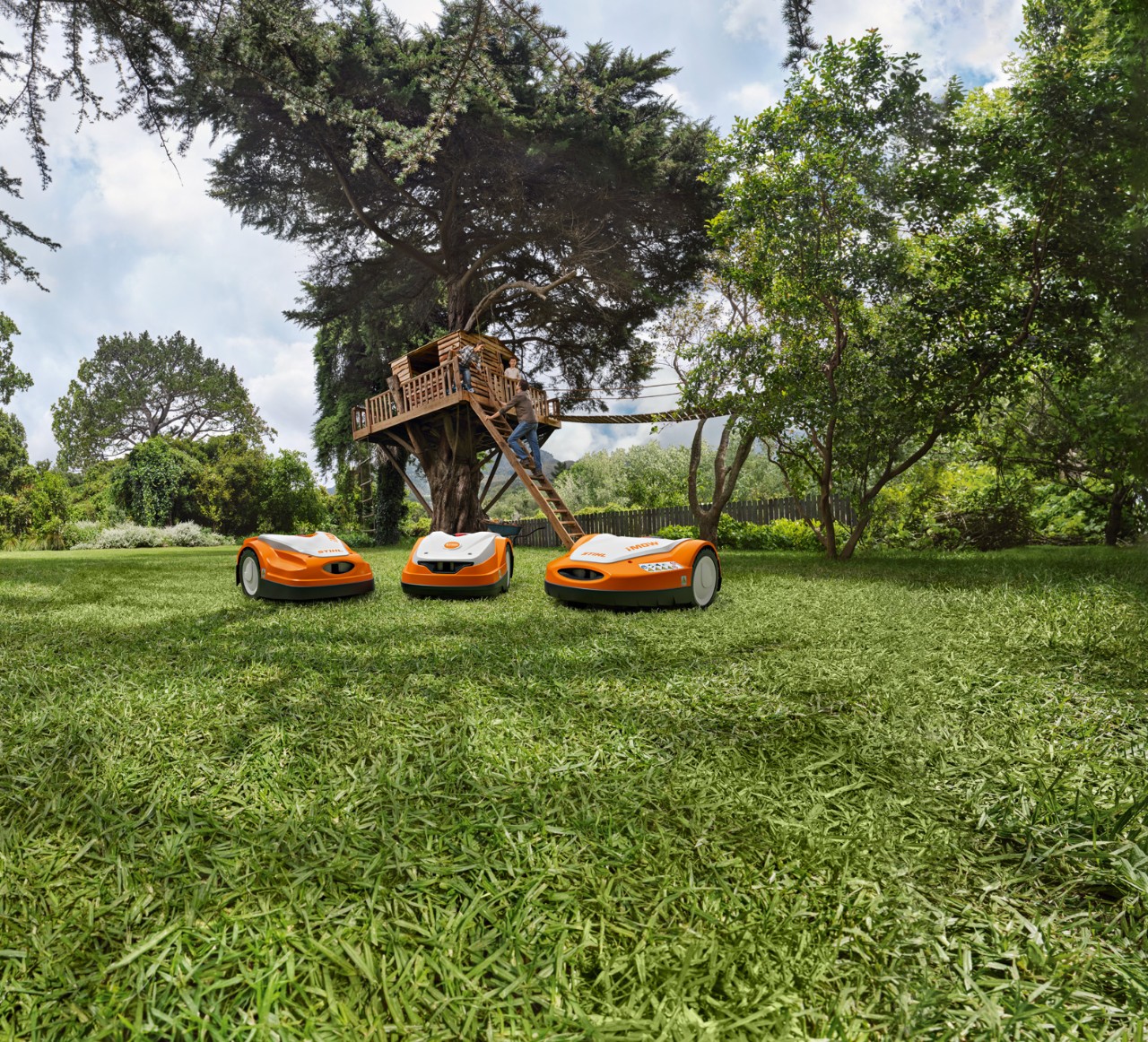 Trois tondeuses robots sur un gazon