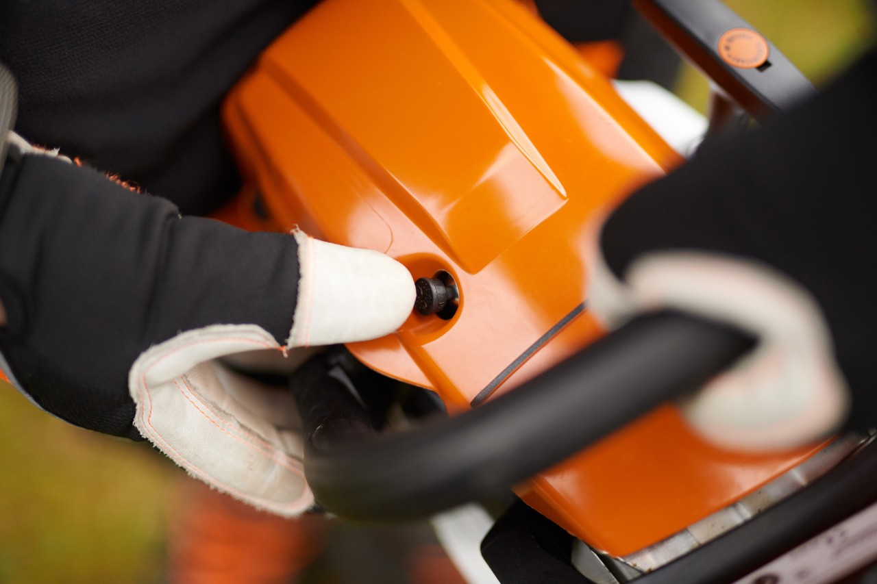 Des mains gantées démarrent une tronçonneuse à essence STIHL MS 261 C-M avec soupape de décompression