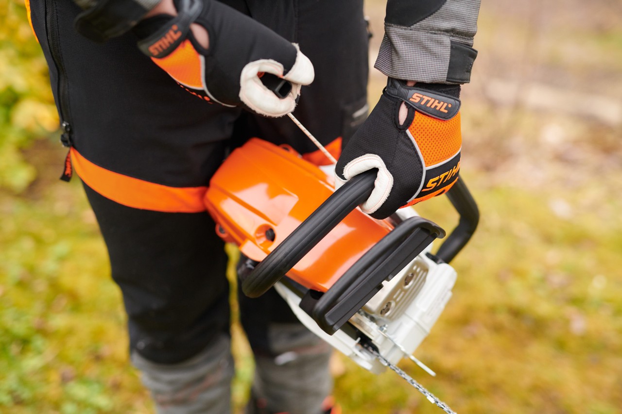 Une personne munie de gants de protection démarre une tronçonneuse STIHL MS 261 C-M avec soupape de décompression